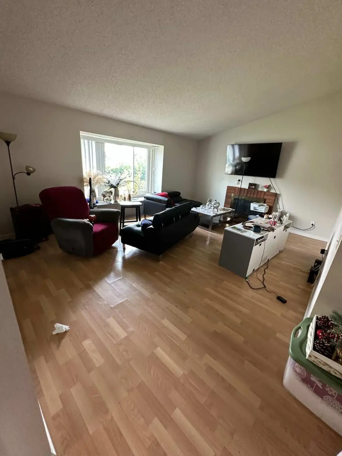 A Moreno Valley living room before a Lumiora cleaning visit, with clutter on surfaces and cords on the floor