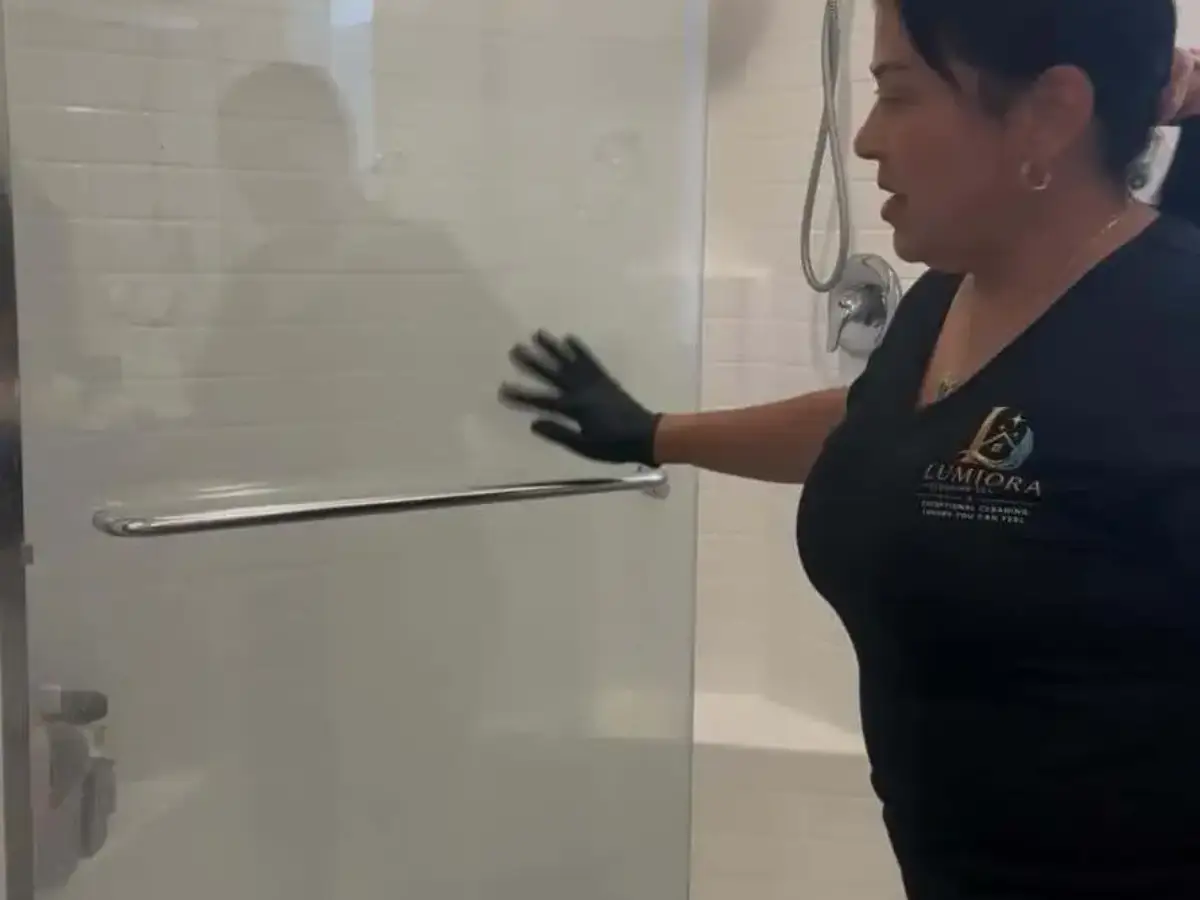 Lumiora team member detailing a glass shower door and bathroom fixtures for a move-in/move-out clean