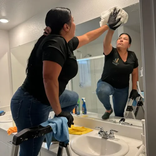 Lumiora team member cleaning a bathroom mirror in a client home