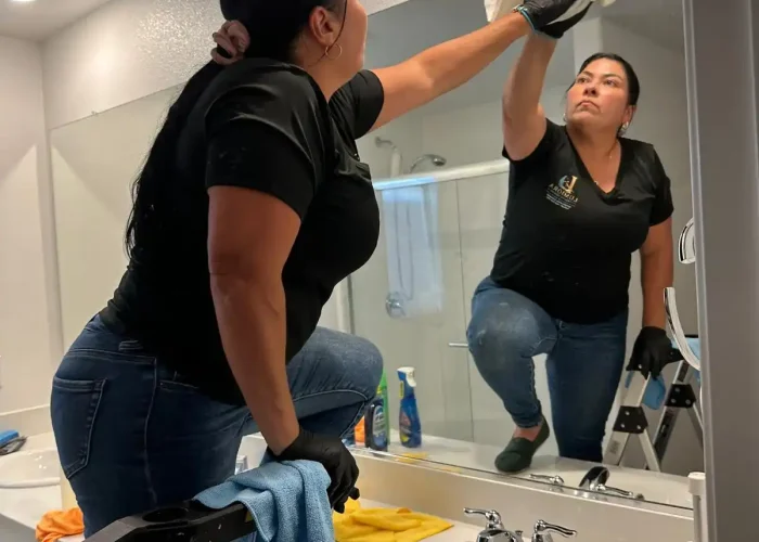 Lumiora team member cleaning a bathroom mirror in a client home
