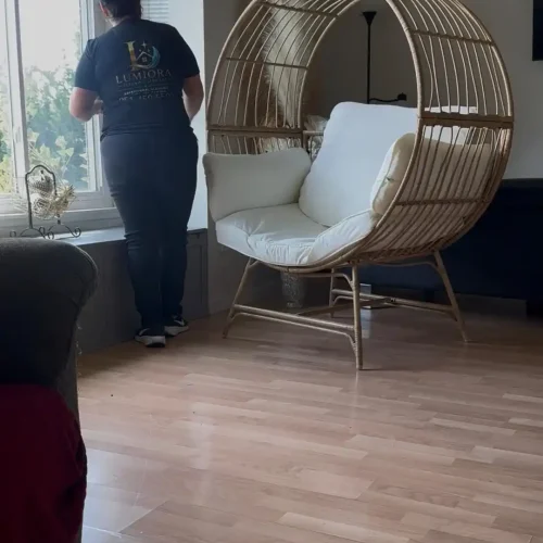 Lumiora team member cleaning a living room window in a client home